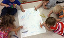 Five Children Coloring A Large Sheet of Paper