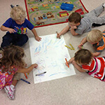 Five Children Coloring A Large Sheet of Paper