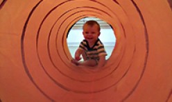 Young Boy Crawling Inside a Colorful Large Tube