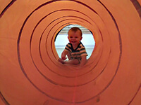 Young Boy Crawling Inside a Colorful Large Tube